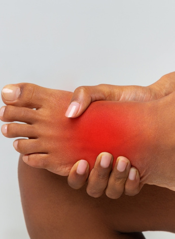 A person clutching their foot, which glows red, representing pain